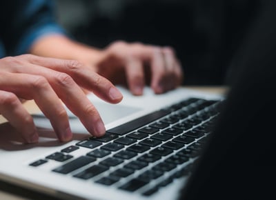 Hände in Aktion auf der Tastatur eines Laptop